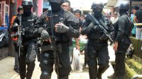 Petugas kepolisian bersenjata lengkap menjaga ketat petugas Den 88 Antiteror Polda Metro Jaya yang membawa barang bukti yang didapat usai melakukan penggeledahan dikediaman Tuah Febriwansyah alias Ust Fahri yang diduga terlibat dalam jaringan ISIS di Setu,
